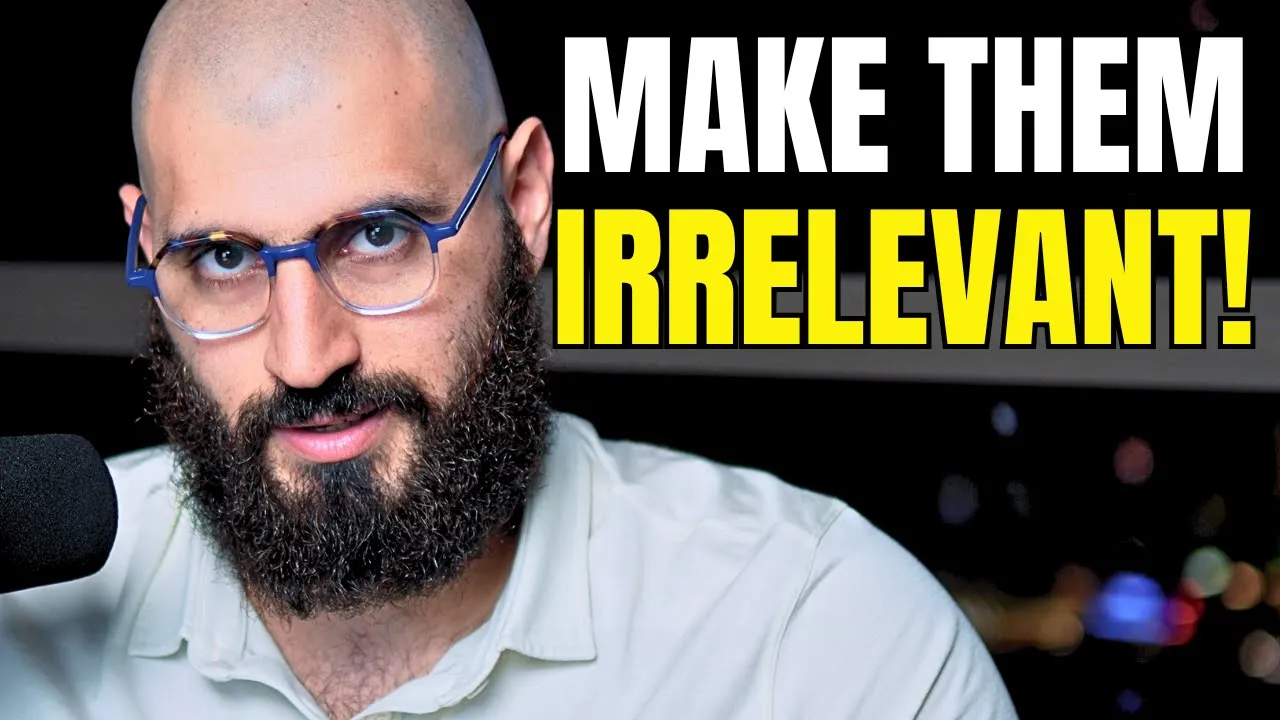 Bald, bearded man wearing blue glasses beside a microphone under the words Make Them Irrelevant